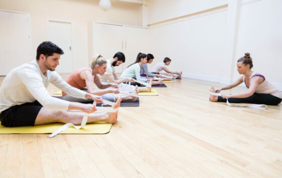 Trainer assisting group of people with stretching exercise